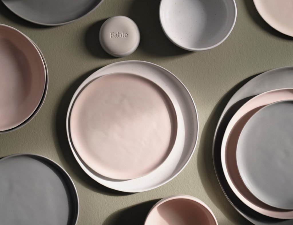 Top-down view of gray, pink, and white dinnerware on a table.